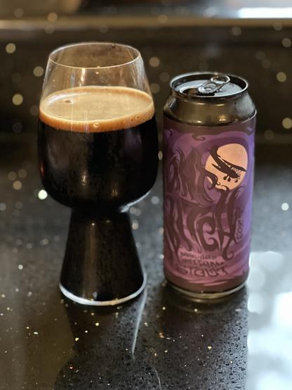 A stout glass next to a pint can with a dark purple label and text in shades of darker purple. An airplane in silhouette flies past the bright pink moon. “Night Witch” is spelled out in wiggly letters