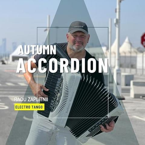 In the middle of a shaded pyramid shape, a grey-stubbled man in a dark baseball cap and white pants plays a white piano accordion with black keys against a backdrop of what looks like an airport or industrial area, all marked roadway, white towers and the pointed tops of canopies.