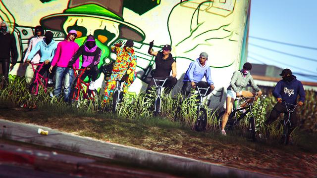 A screenshot I took in the video game GTA Online using the Rockstar Editor. It shows members of the crew BONK dressed with hoodies and masks sitting on BMXs in front of the famous South Los Santos mural.