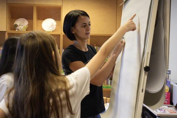 Das Bild zeigt eine BfDI-Mitarbeiterin, die Kindern das Erstellen eines sicheren Passworts erklärt.