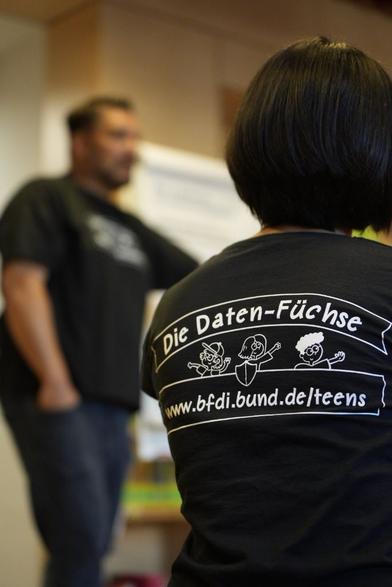 Das Bild zeigt zwei BfDI-Mitarbeitende, die T-Shirts mit dem Logo der Daten-Füchse tragen.