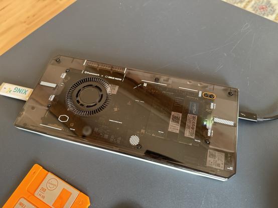 Laptop motherboard inside a transparent case sitting on a desk.