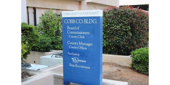 Cobb County government building sign, a vertical rectangular sign with the words "Board of Commissioners," "County Clerk," "County Manager," "County Office," "Employment," and a wheelchair entrance icon