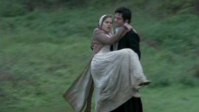 A man carries a woman in his arms, hurrying down a slope