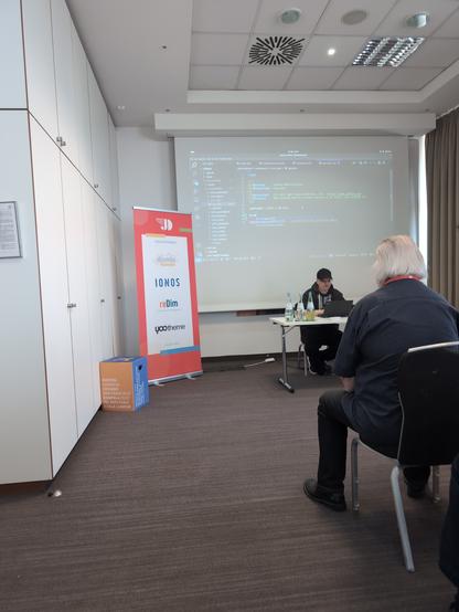 Benjamin Trenkle sitting in front of a table talking and using his laptop.