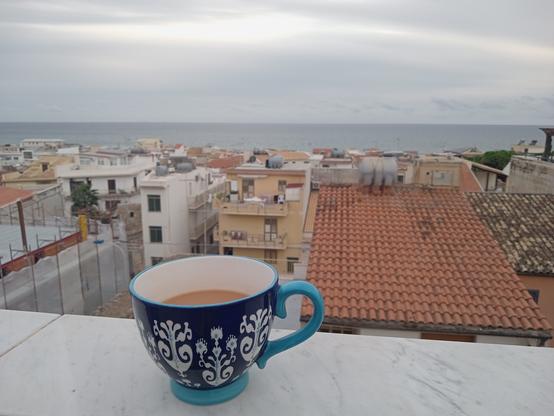 Una tazza di tè blu sul davanzale, sullo sfondo il mare.