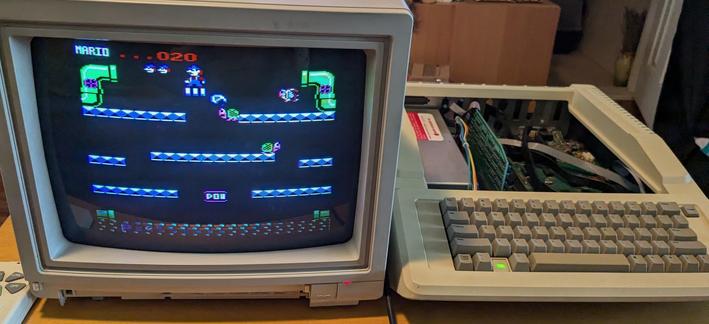 Old color CRT monitor displaying the Mario's bros game next to an open Apple IIe computer.