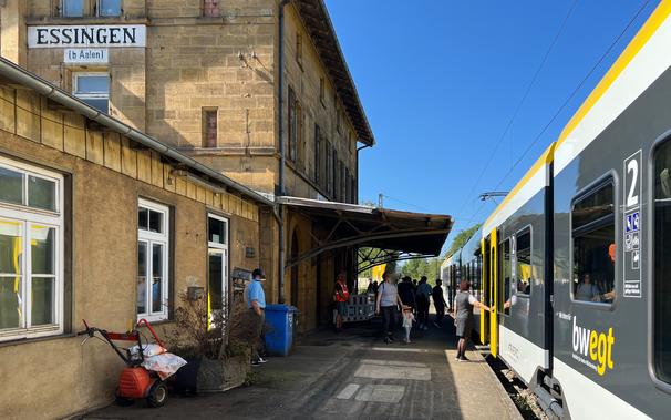 Blick auf den Bahnsteig und das Bahnhofsgebäude von Essingen mit haltenden bwegt Flirt von bwegt und ein- und aussteigenden Fahrgästen