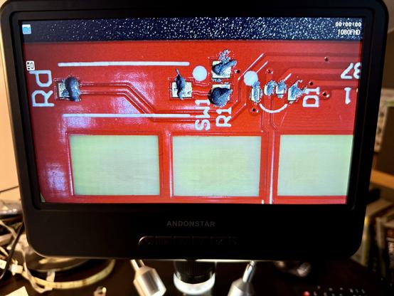 Electronics microscope screen showing a section of the 44con badge with blobs of solder paste on the pads