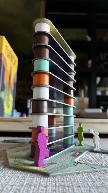 A tower of game components from the board game Flatiron are stacked up to resemble the actual Flatiron building.