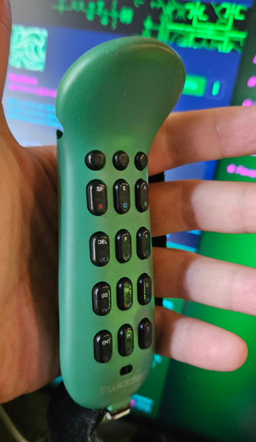 Close-up of the Twiddler one-handed chorded keyboard. Twelve pill-shaped keys and three smaller buttons.