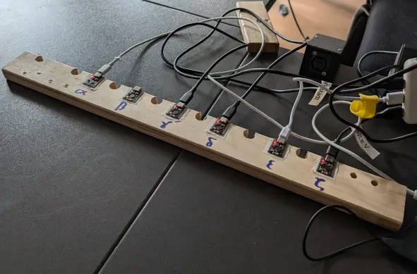 A piece of wood with 6 ESP32 supermicro boards taped to it. They are blinking but you cant see that because its not an video.