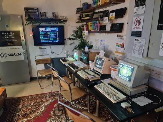 A view of the UK computer room, showing (from left to right)  Ceefax on a TV (with current information!), A BBC B showing Brian Clough's Football Manager, A BBC Master with a list of software on the fake floppy drive, a BBC Electron showing Crazee Rider high scores, and Acorn Archimedes A4000 showing a game I can't remember!

Various Spectrum models are hanging on the wall behind the playable machines.

Out of shot (behind me) was a Dragon32