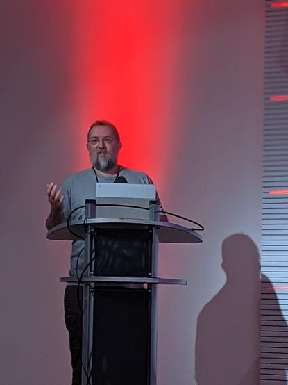 a relatively flattering picture of the author stood at the conference podium while backlit with a red light.
