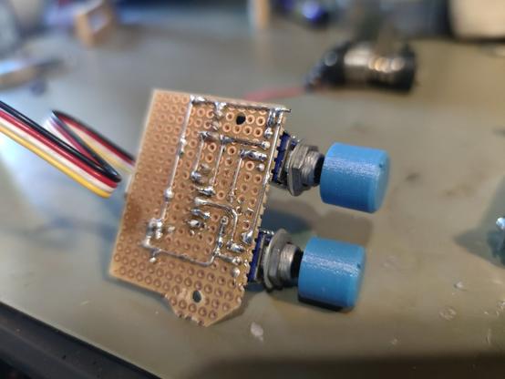 The underside of a protoboard with wire soldered to the surface forming the traces. There are two potis with 3d printed caps and a 4pin cable attached to the board.