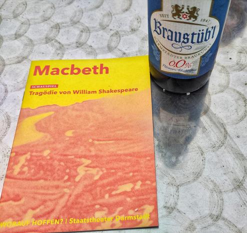Foto: Theaterprogrammheft MacBeth und eine Flasche Braustübl 0,0 auf Metaloberfläche.