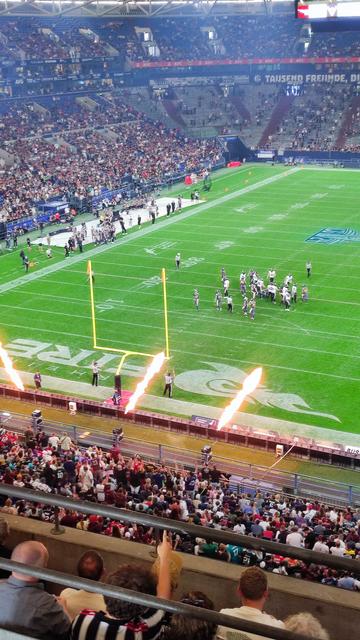 Football Feld, in einem Stadion. Das Team Rhein Fire hat gerade Punkte gemacht und es wird mit Flammen gefeiert.