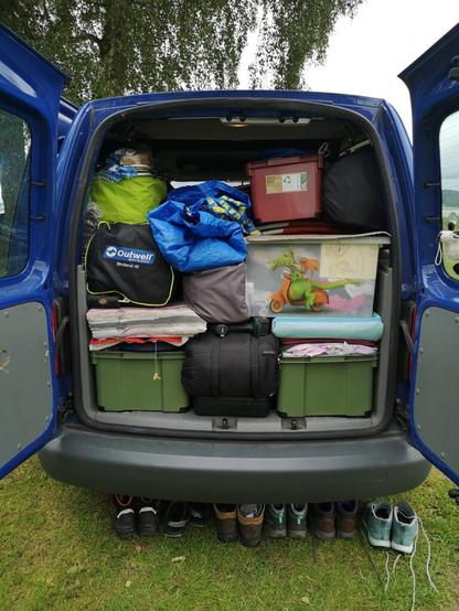 Blick in den Kofferraum eines VW Caddy, das mit Campingartikeln schon beladen ist