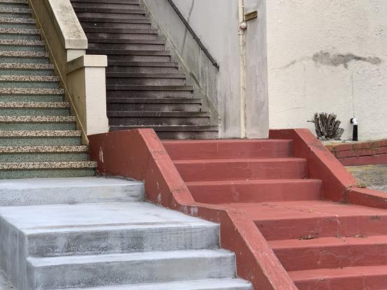 side by side staircases, each in segments. The lower steps on the left are white, on the right, red, then each turns sort of off-white with green marble sides on the left staircase.