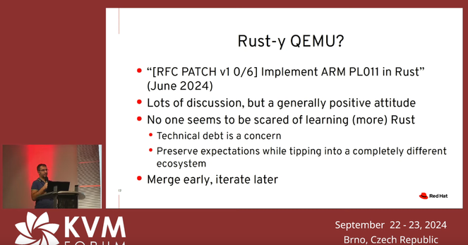 Slide from a conference presentation. The speaker, Paolo Bonzini, is shown at the right. The verbatim content of the slide follows:

Rust-y QEMU?

- “[RFC PATCH v1 0/6] Implement ARM PLO11 in Rust” (June 2024)

- Lots of discussion, but a generally positive attitude 
- No one seems to be scared of learning (more) Rust
- Technical debt is a concern
- Preserve expectations while tipping into a completely different ecosystem
- Merge early, iterate later