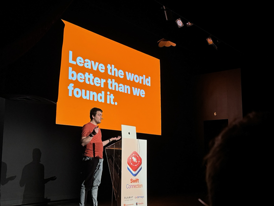 Bas on stage with a slide behind him that says “Leave the world better than we found it”