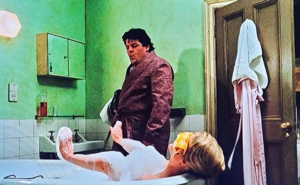 Robbie Coltrane in his 20s or 30s has walked into the shared bathroom the Griswold Mom is in a bubble bath with a washcloth over her eyes. He is checking her out while he whistles.