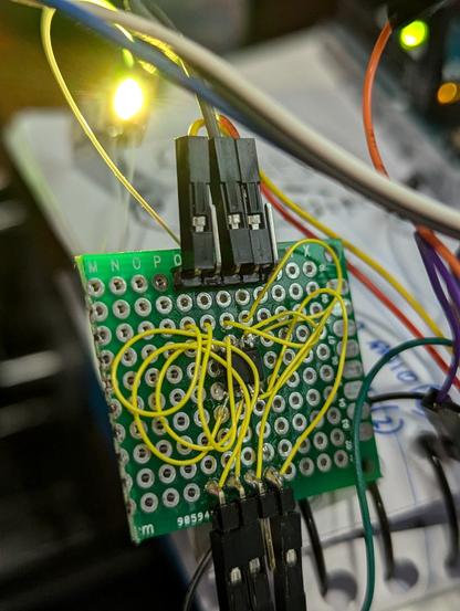 A chopped up bit of perfboard with a sop-8 micro poorly soldered into it and a rats nest of awg28 wires connecting the micro's pins to some DuPont headers.