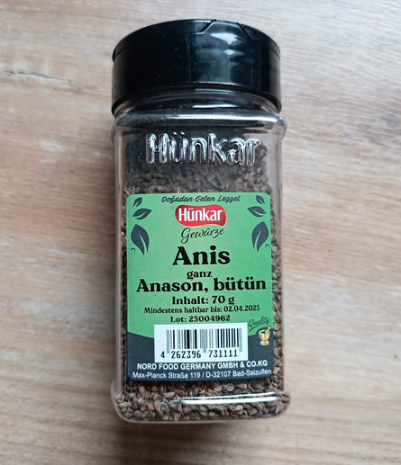 Auf dem Tisch liegt eine Packung  Anis ganz (Anason, bütün)
In der Verpackung sieht man die kleinen ganzen Samen