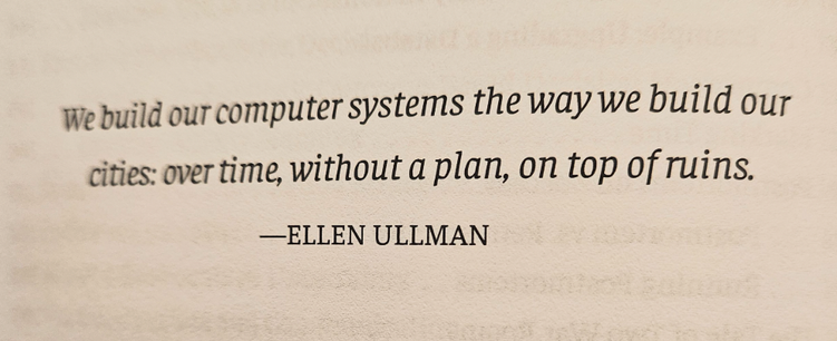 A book page saying: We build our computer systems the way we build our cities: over time, without a plan, on top of ruins.