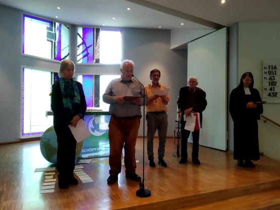 Menschen stehen vor Mikrofonen im Altarraum einer Kirche