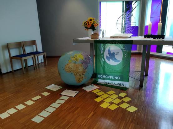 Ein Altartisch mit Christians4Future Flagge, einer Erdkugel, Blumen, Kerzen, der Bibel und Karteikarten.