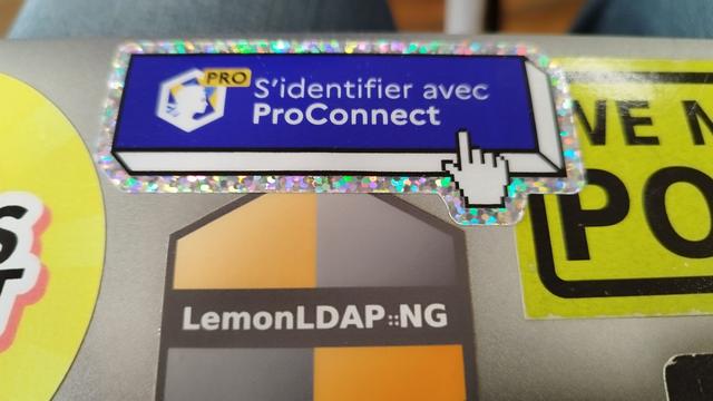 Coque d'un ordinateur portable avec un autocollant pailleté "S'identifier avec ProConnect" et un un autocollant LemonLDAP::NG.