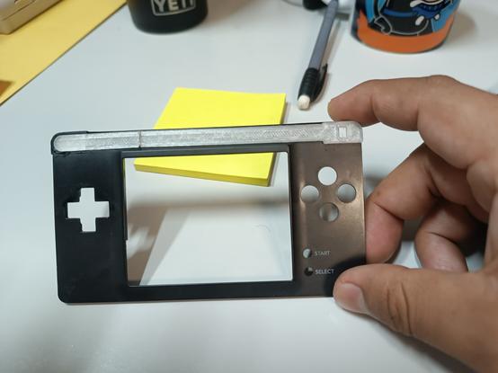 La parte "transparente" es una pieza de relleno para aplanar el hueco que deja la ausencia de la pantalla superior, la idea es usarla tal cual o de base para un mejor acabado y posteriormente pintar.
Está partida porque acostumbro imprimir versiones para cortar y ajustar en físico