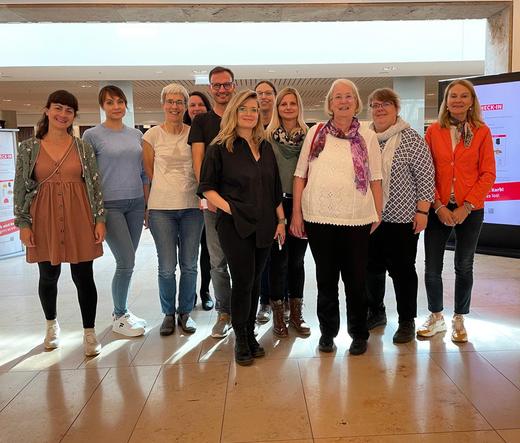 Eine Gruppe von Menschen steht im Foyer der SLUB Zentralbibliothek. Sie lächeln.