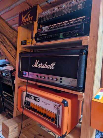 Photo d'un rack en bois avec un empilage d'ampli guitares et basses à lampes.