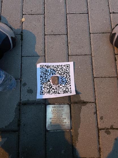 Foto von Stolperstein nach Reinigung mit ausgedrucktem QR Code zum Eintrag https://stolpersteine-guide.de/map/biografie/1214/lina-marie-schobel