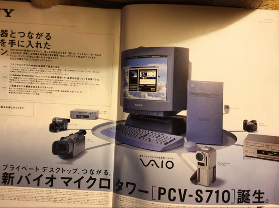 A photo of a double-page spread ad, very elegant, for a PCV-S710 desktop. It's a soft denim blue in colour, monitor, keyboard, mouse, and the micro-tower that's only half the height of the monitor on its pedestal. Various pieces of audio-visual equipment are arrayed around it, indicating that this isn't for playing Quake and Half-Life on.