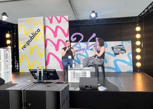 Isabelle Bartram und Lyndsey Walsh sitzen auf einer Bühne und reden. Im Hintergrund sind bunte Farben und der re:publica-Schriftzug