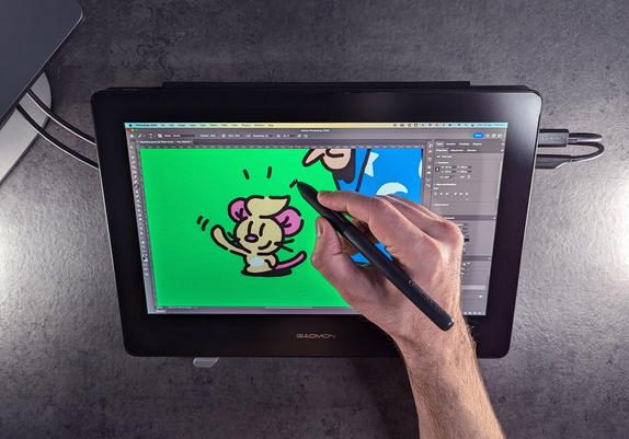 A person using a stylus on a graphic tablet to draw a small rodent creature, on a green background.