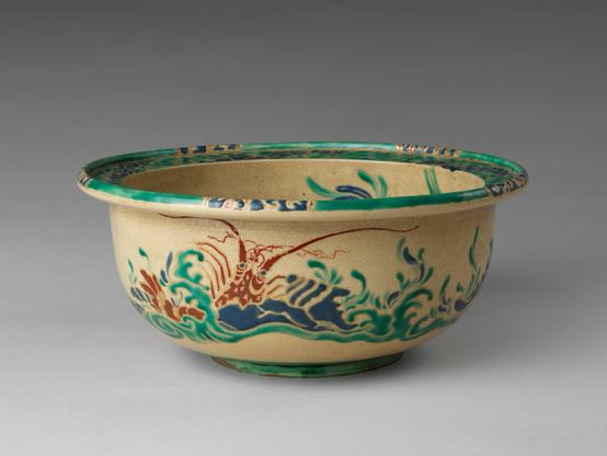 official museum photo of the object, side profile on gradient grey background: polychrome bowl (red/green/blue on yellow) with underwater design featuring a Japanese Lobster