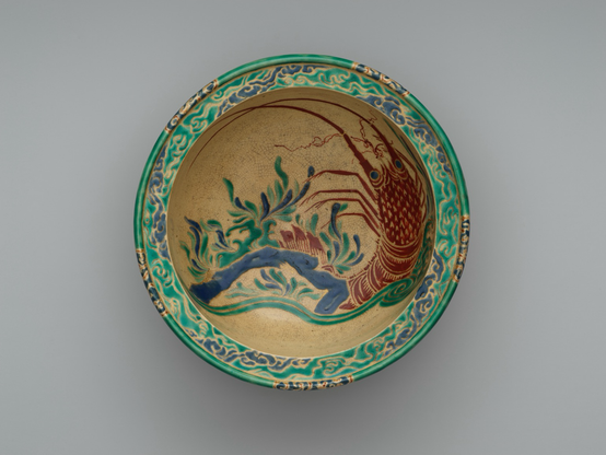 official museum photo of the object, top down view on gradient grey background: polychrome bowl (red/green/blue on yellow) with underwater design featuring a Japanese Lobster