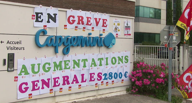 L’entrée du site Capgemini avec son logo est redécoré avec les revendications des salariéEs : « En Grève Augmentations Générales 2800€ »