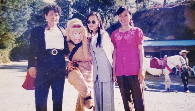 My Mom, me & my 5th Auntie with an entertainer dressed up in a monkey costume.
There's a man in cowboy hat, leading a red saddled, white horse, in the background.