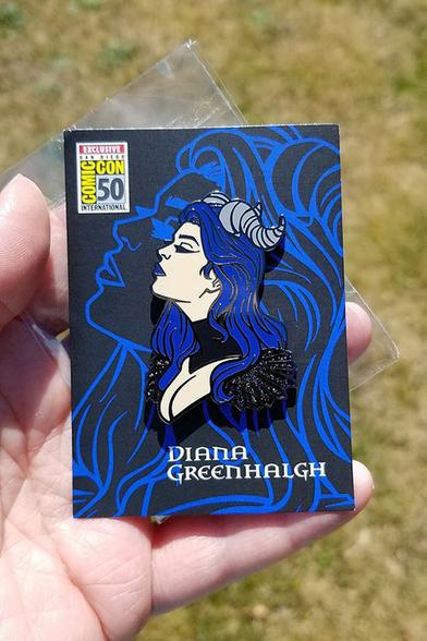 A shot of the SDCC50 official exclusive variant of my first pin design. This one has blue hair and lips, shifting holo glitter accent on the shoulder epaulets, and is on an official exclusive backing card.