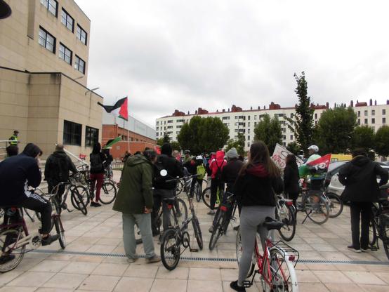 Gente con sus bicis delante de la Facultad de Educación. Se ve alguna bandera palestina.