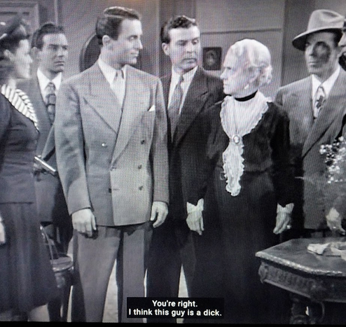 A screenshot from an old black and white 1950s movie. We see four men and two women in a room wearing trendy fashions from the time period. One of the women and one of the men are staring at each other angrily. 

The Closed Caption at the bottom of the photo says: 

"You're right. I think this guy is a dick."

["Dick" is old-fashioned derogatory slang for "policeman."]