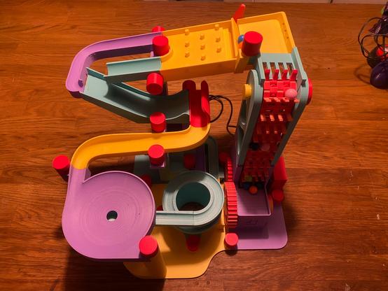 Photo of a 3D printed marble machine in several different colors. There is a marble elevator to the right that moves marbles to the top.
