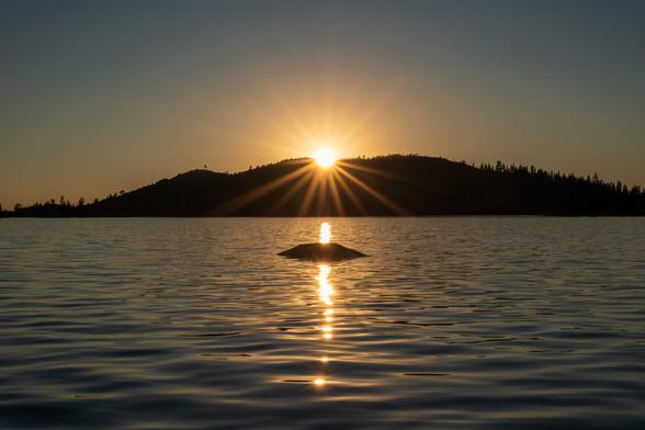 The sun sets behind a hill, viewed from on the water. [Fuji X-T5 / 16-55 2.8]