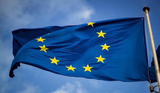 Eine blaue EU-Flagge mit gelben Sternen weht an einem Fahnenmast.