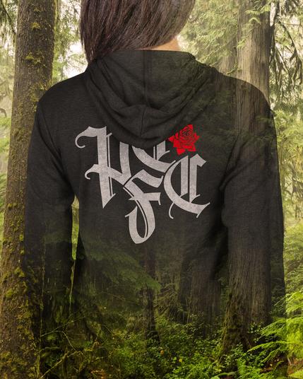Back of a women wearing a black hoodie with a great and red blackletter PTFC design, semi-transparent to the old-growth forest behind her.